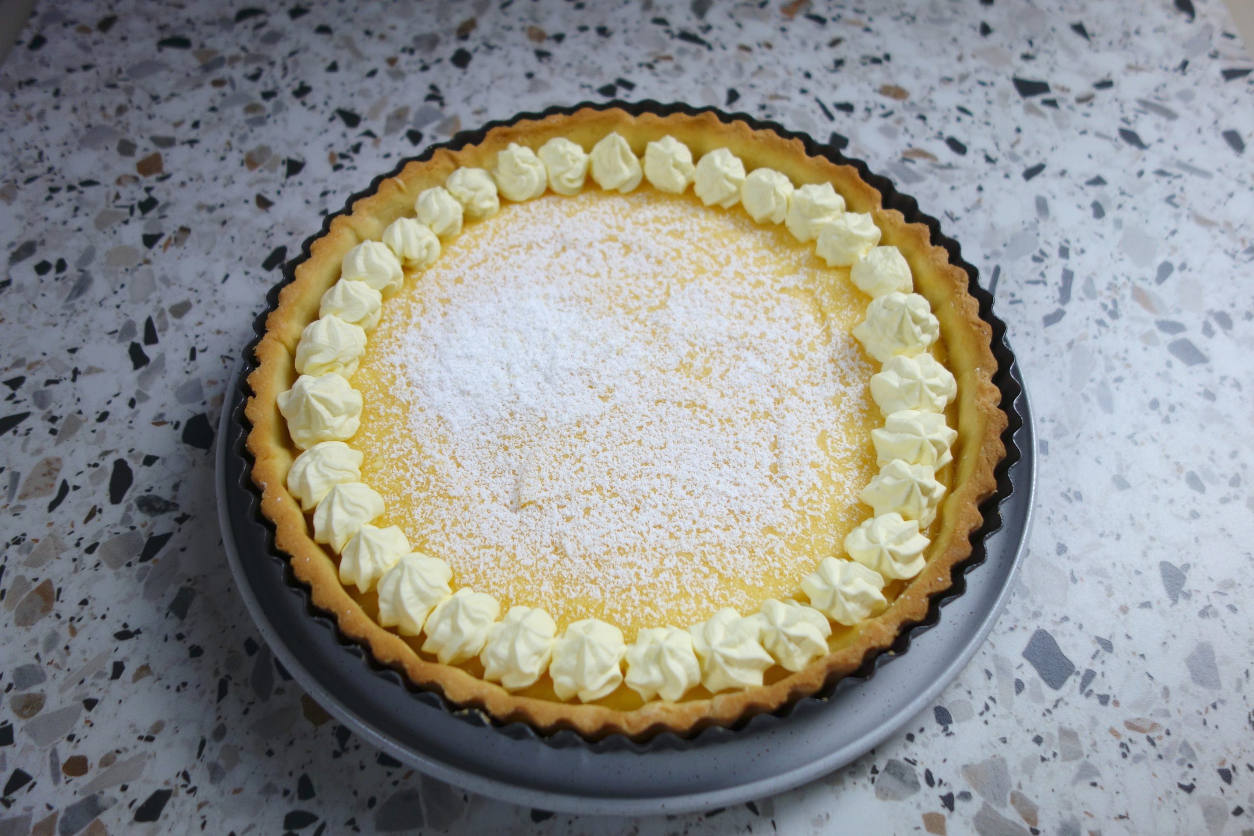 lemon tart with cream and powdered sugar garnish