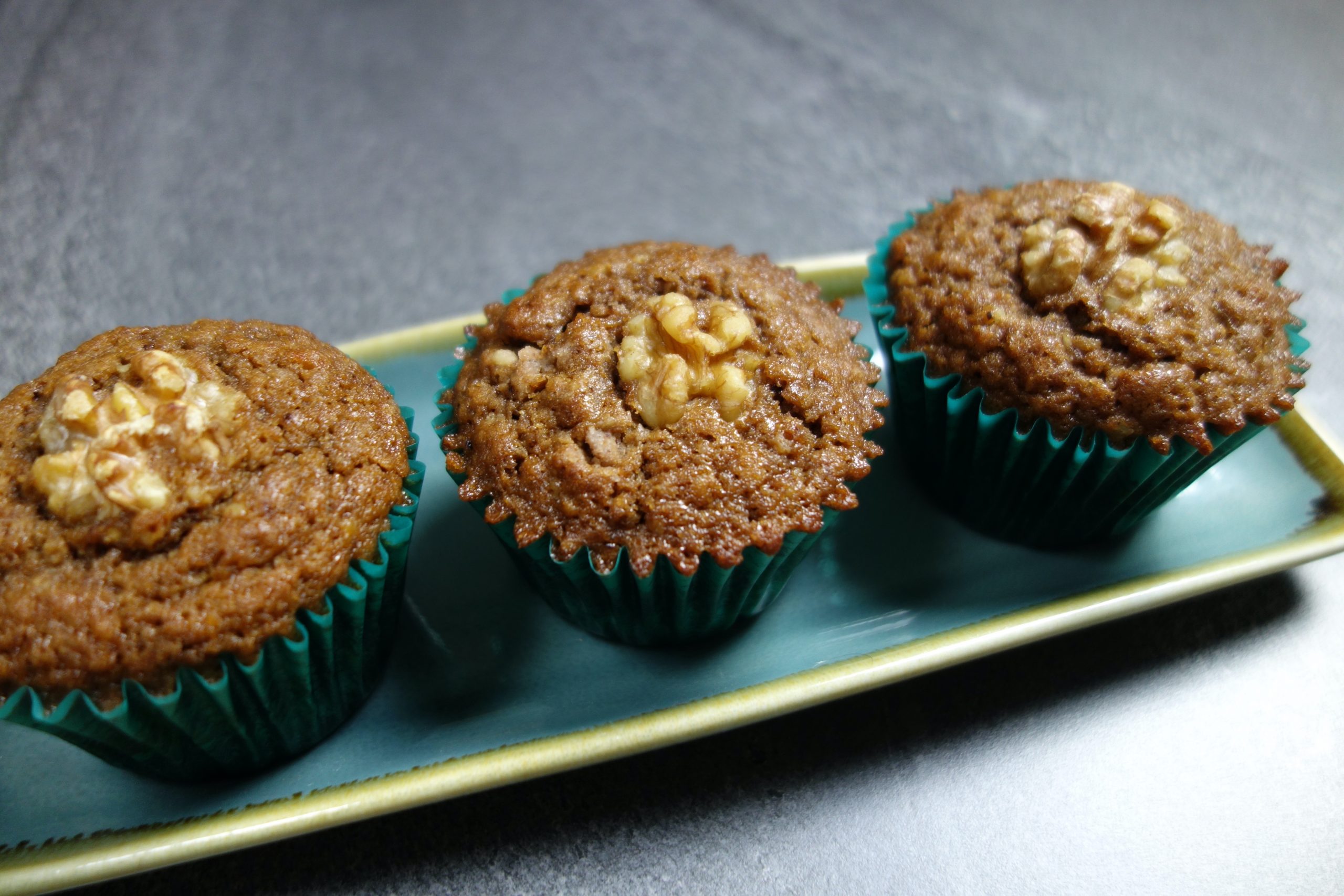 three coffee and walnut muffins lined on a rectangular plate